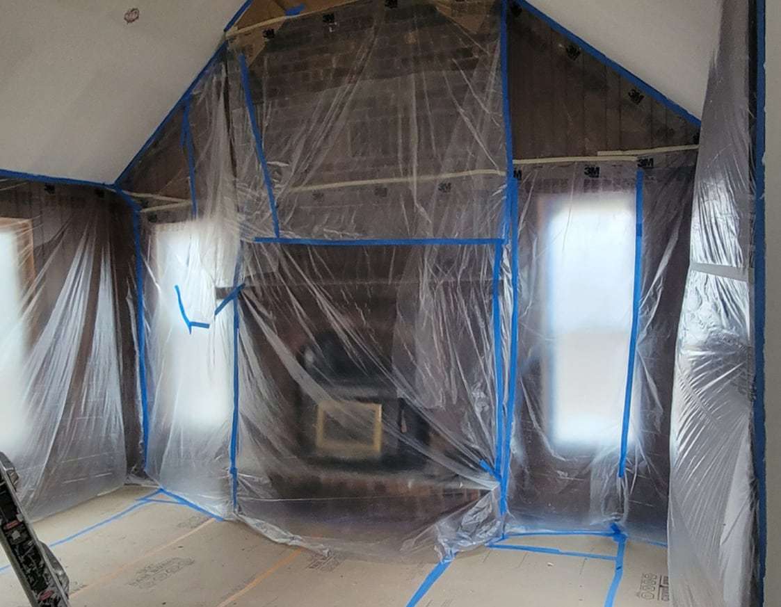 During preparation: the entire room sealed in clear plastic sheeting taped at every edge, floor covered