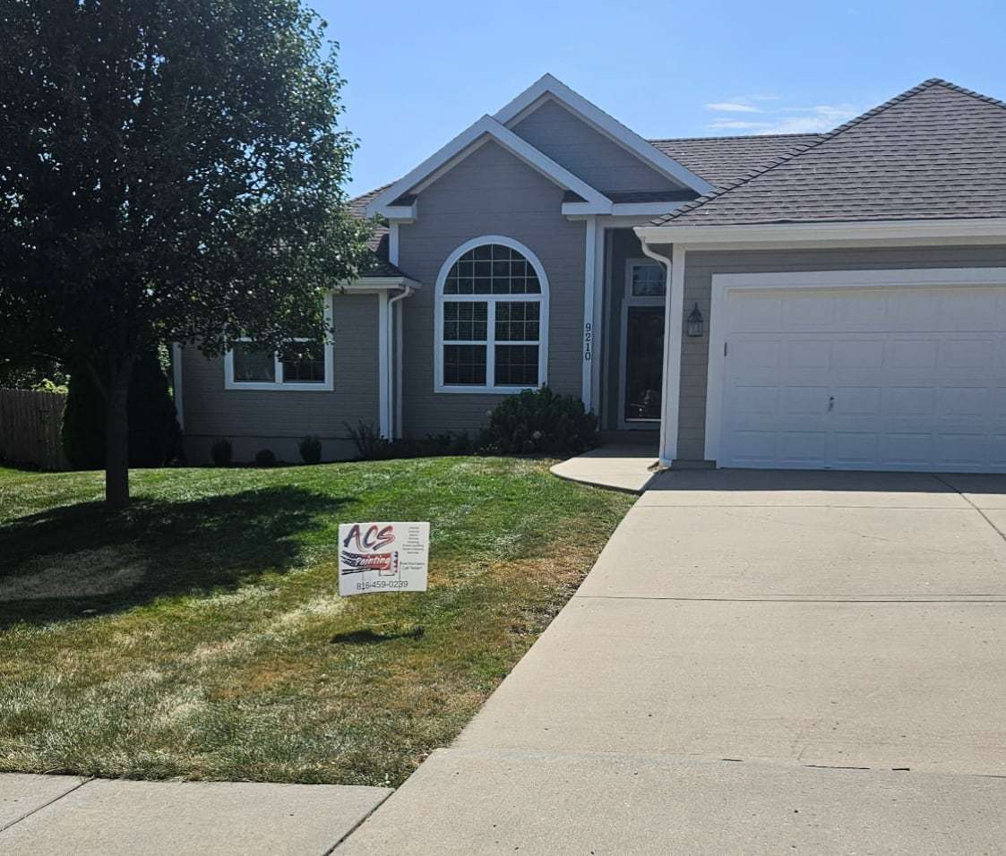 Single-story home after repainting in gray with white trim and a white garage door