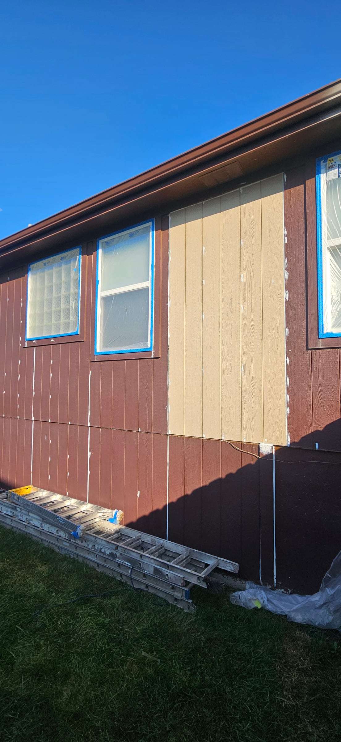 Damaged section of maroon panel siding next to a window