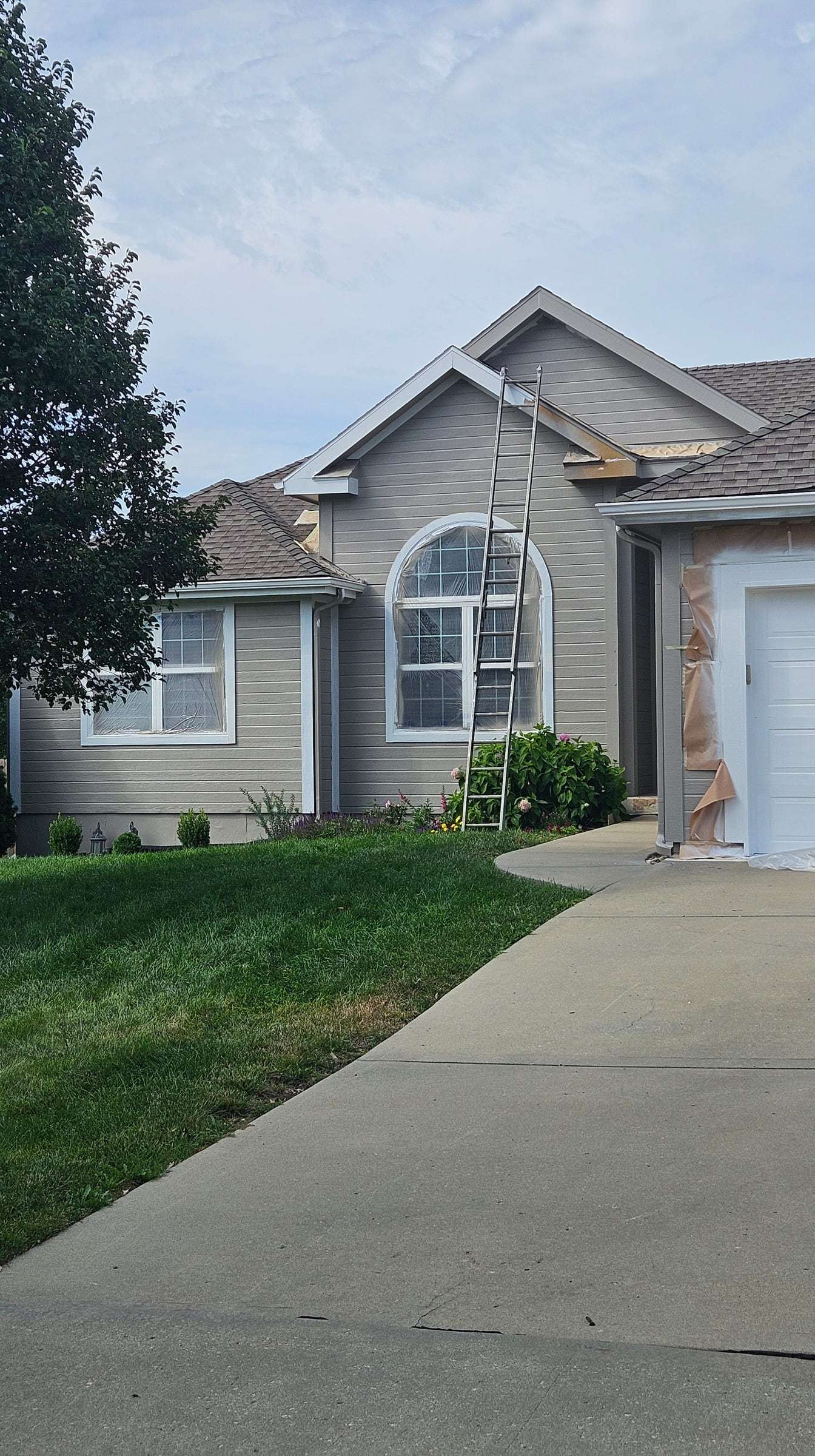 Front of the home part-way through painting, garage door still masked with paper