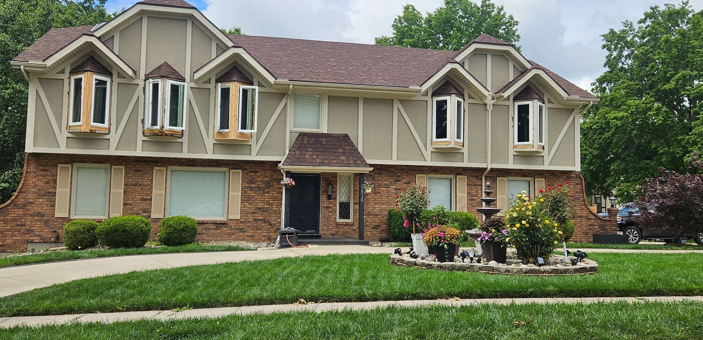 Before: beige siding panels with brown half-timber trim over an orange-red brick base